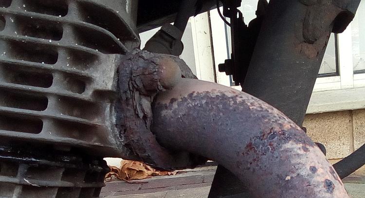 The old exhaust on the 125 covered in rust at the header