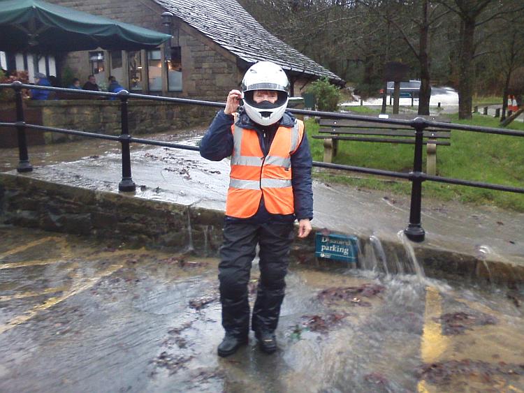 Wearing all her bike kit Sharon stands in pouring rain and floodwaters