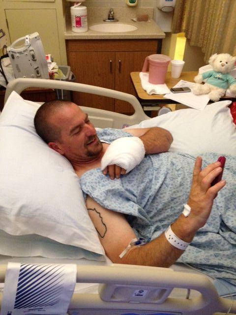 Stephen laughing in a hospital bed with his hand all bandaged up.