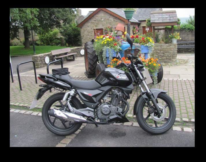 The Keeway RKS125 looking fabulous in front of a flowers and a tractor