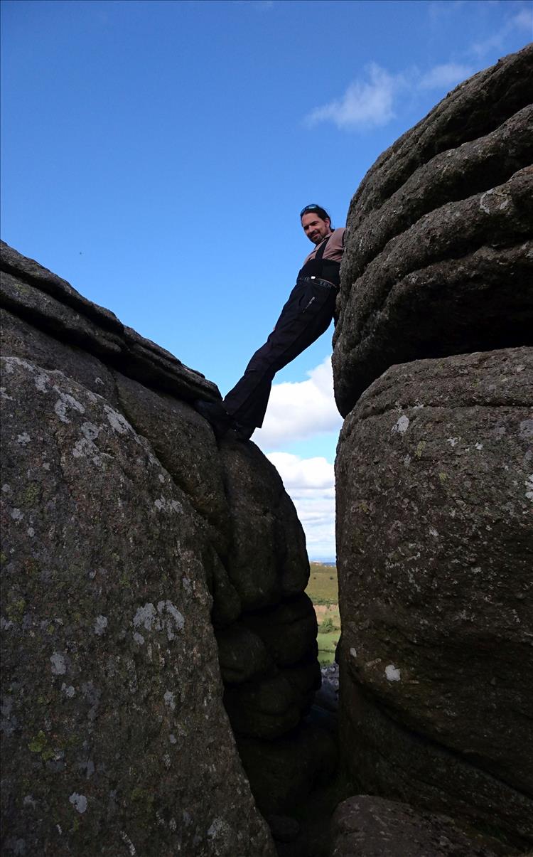 Ren is high up in the crevice between rocks looking down at the camerA