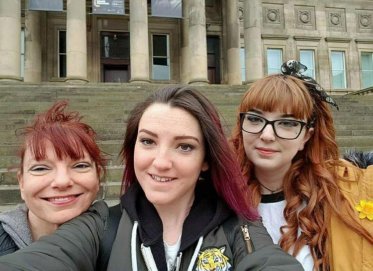 Sharon and her 2 young adult daughters, smiling and laughing into the camera