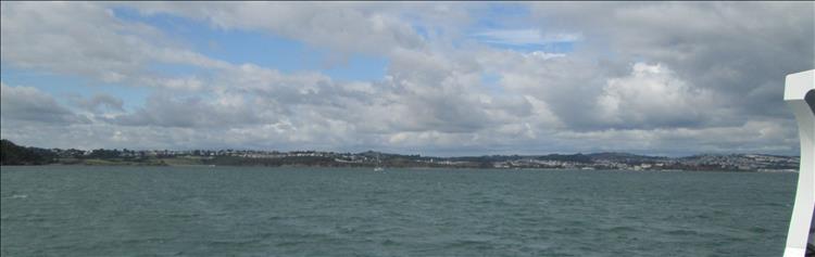 A long strip of distant shoreline with towns and green areas just visible