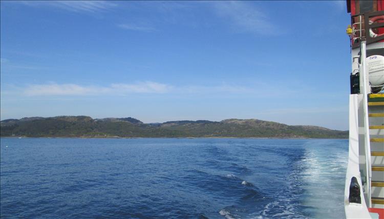 calm waters blue skies, the wake of the ferry and the rugged shoreline of loch Fyne