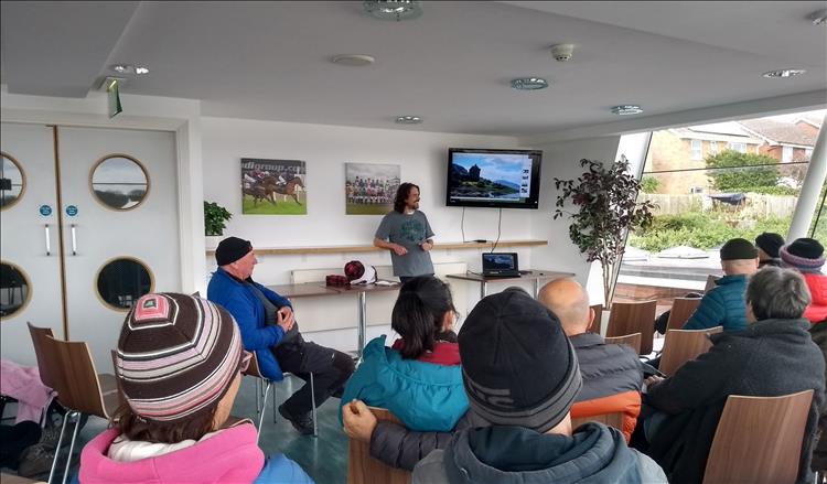 Ren stands in front of a small group of people as he presents his talk about Scotland