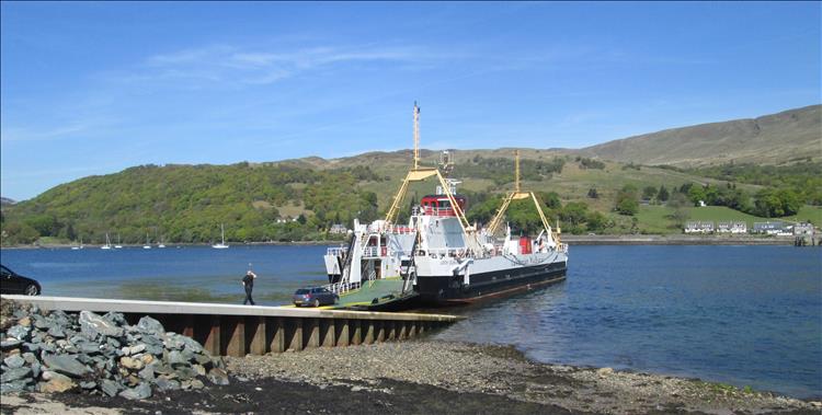 The ferry from Bute to the mainland on the northern tip. Blue skies, tree covered hills and the calm loch