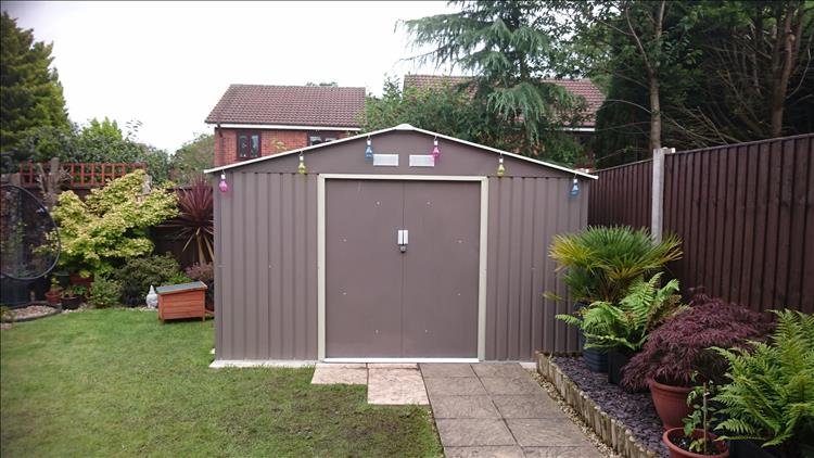 The new shed seen from the front. Made of metal and looks huge compared to the old shed