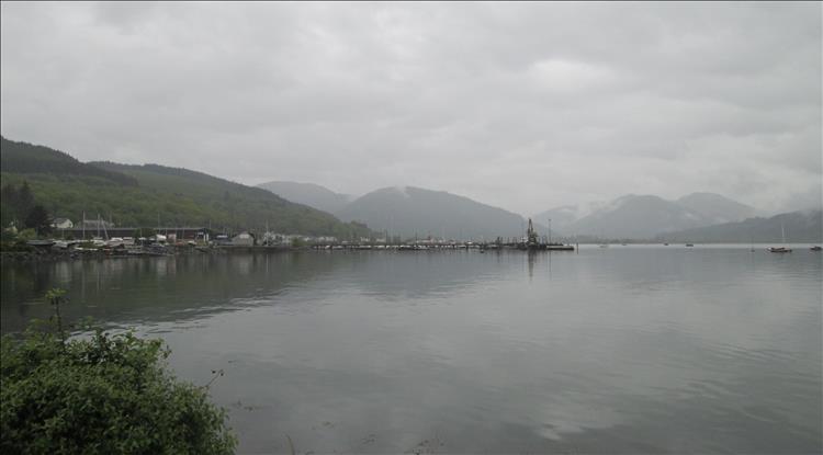Calm flat waters of the sea loch with mist covered hills in the distance