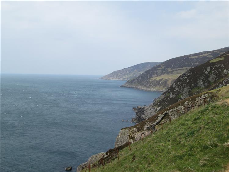 Rocky promontories plunge into the calm sea in a dramatic shoreline vista at the Mull