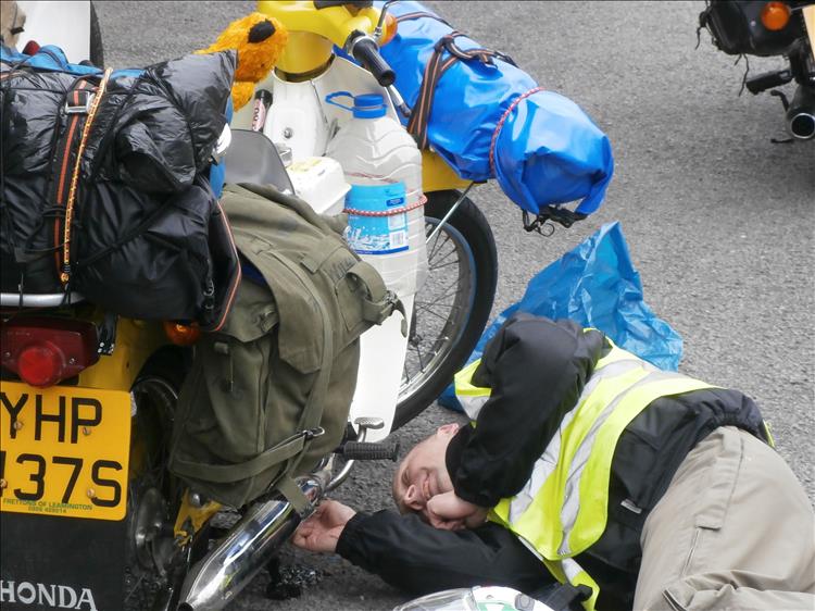 Andy lays on the ground tinkering with the underside of his loaded C90