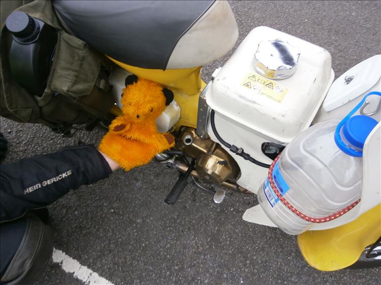 The puppet sooty beside the now golden coloured engine cases of the overheated motorcycle