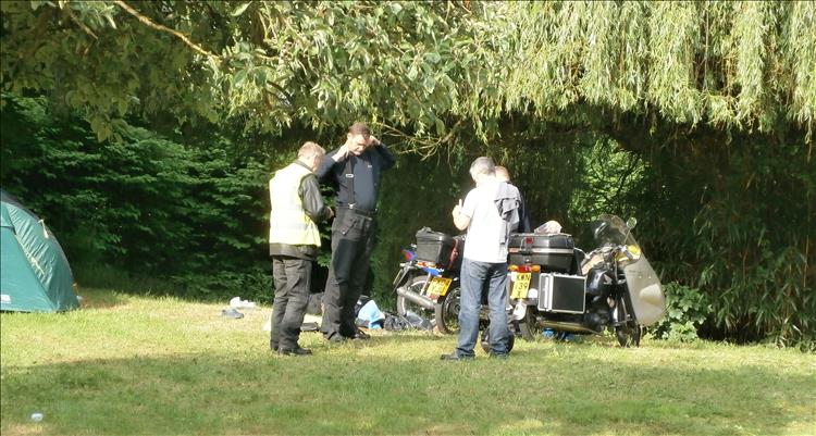 A bunch of chaps with tents and a curious display of motorcycle at Guines