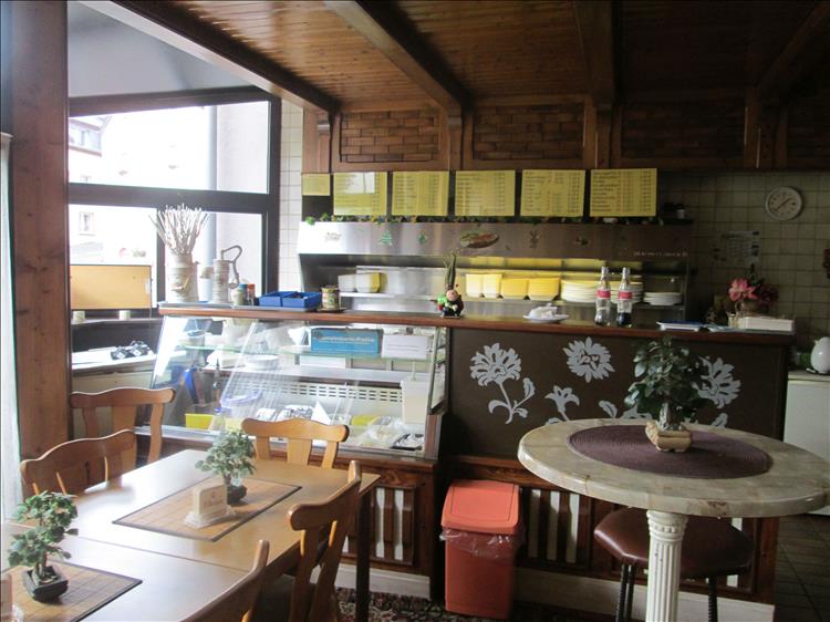 Inside of the cafe with wooden panels, table, chairs and an old glass counter