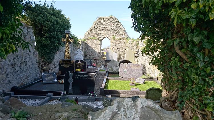 The ruins of a small chapel with modern crisp gravestones where the congregation once sat