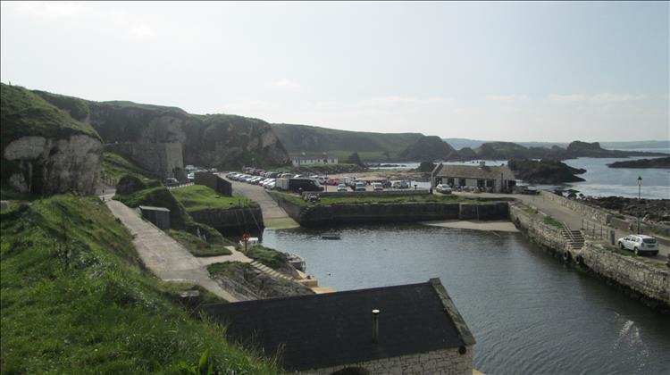 Ballintoy Harbour. Sturdy walls and buildings at the foot of steep cliffs on the Irish coast