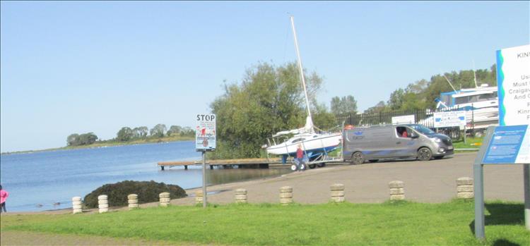 A sailing boat on a trailer behind a grey van