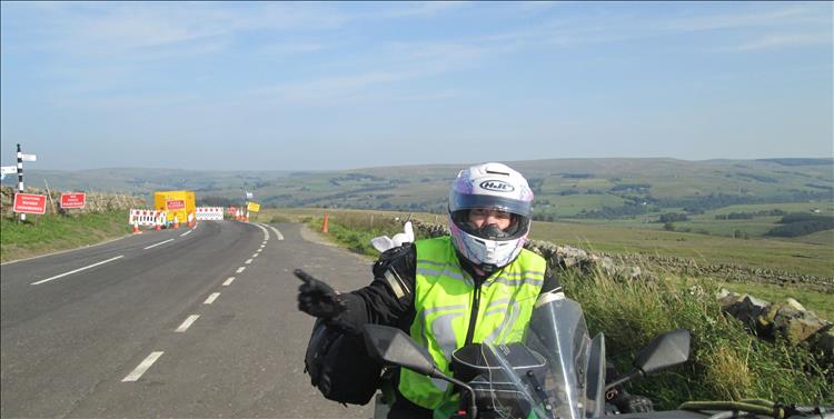 The road is closed and Sharon is pointing in the delightful scenery