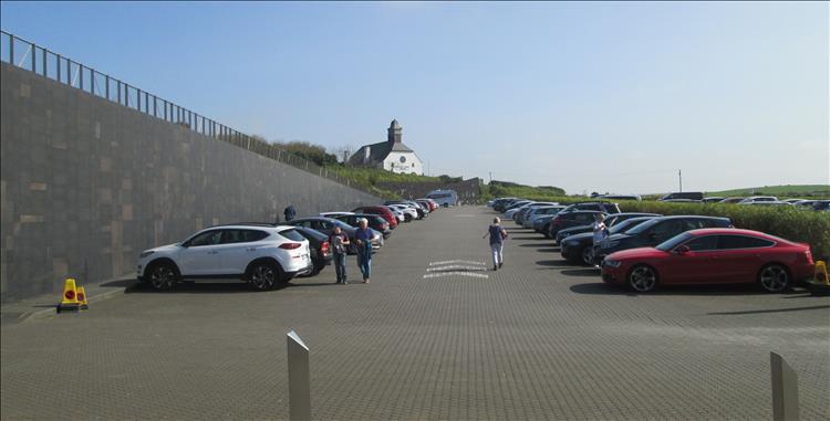 A large car park and stout almost fortress like modern wall at the Giant's Causeway
