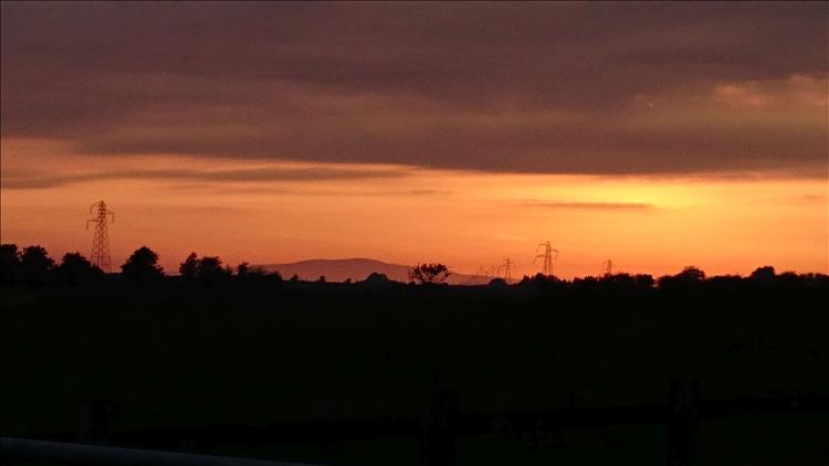 Deep dark orange skies, the outlines of pylons and a menacing feel to the evening sky