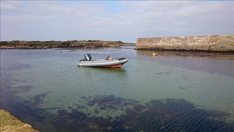 A RIB boat in the calm waters and hazy blue skies of the sheltered harbour