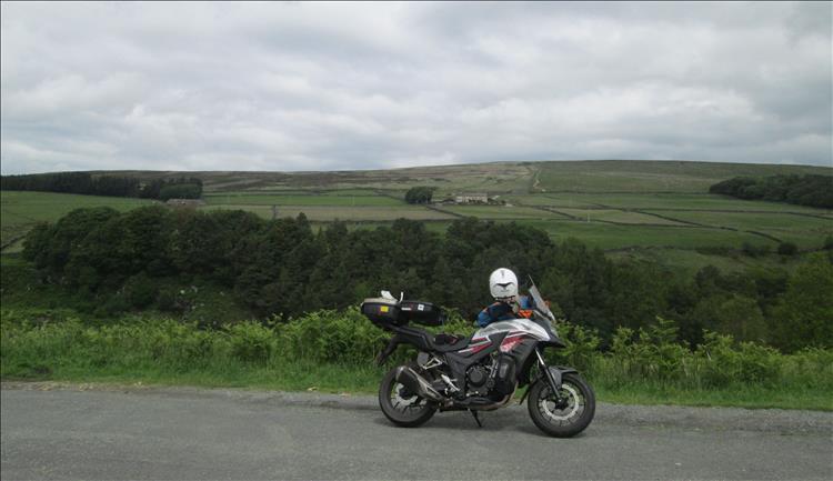 Rens motorcycle set against the farmland and trees and hills