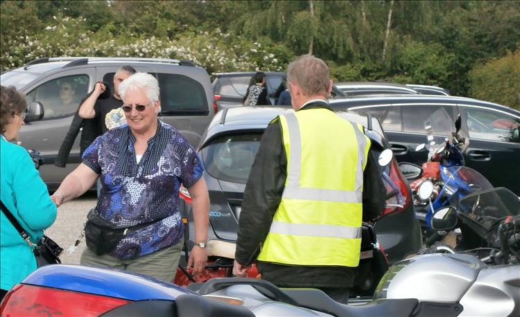 People milling around in the car park, we see a rider talking to an older lady