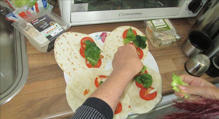 Sharon is preparing tortillas with pepperoni and salad and coleslaw