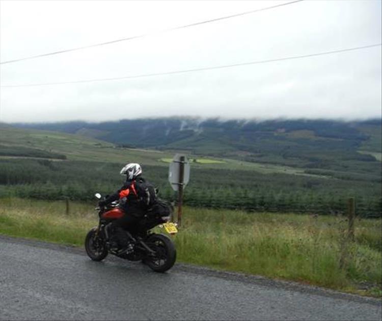 A rider on his motorcycle under heavy skies getting very wet