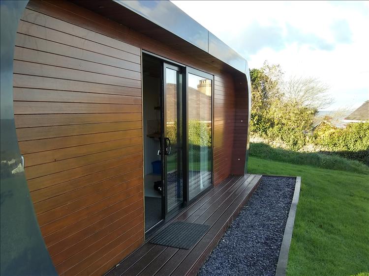 A large wooden and steel chalet with sliding doors and a view over the sea