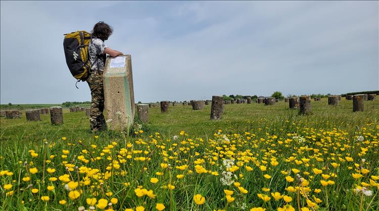 Ren stands with a massive bag on his back looking over a meadow with concrete stumps