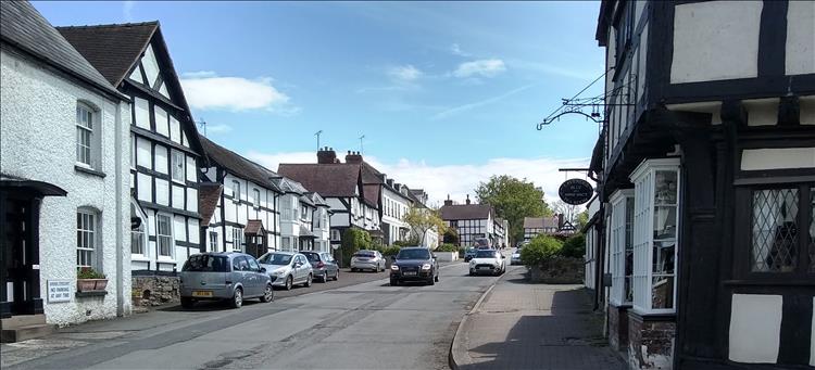 Old timber framed buildings, a quiet open street and swinging shops signs