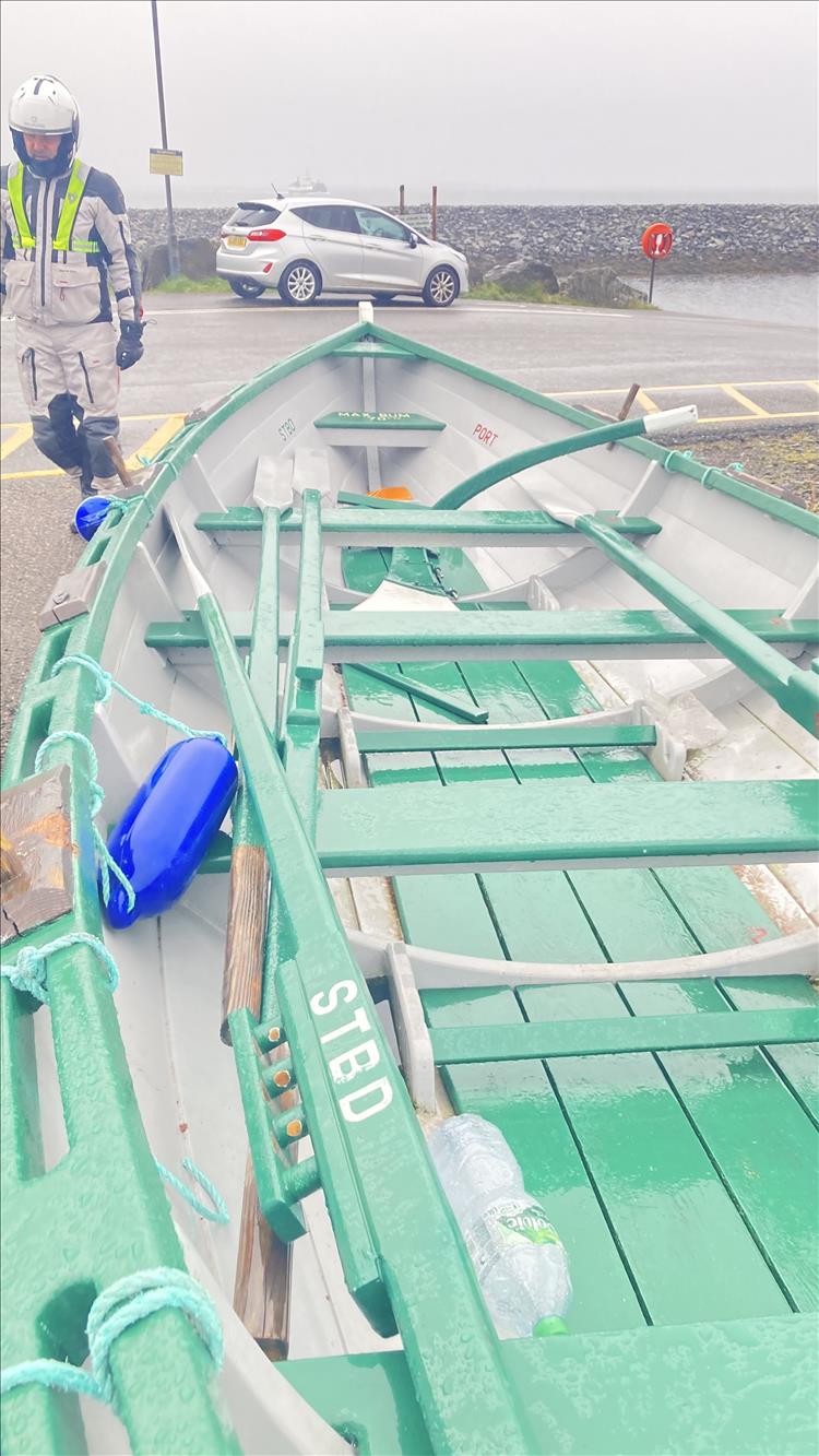 A smart white rowing boat with green trimmings in the rain