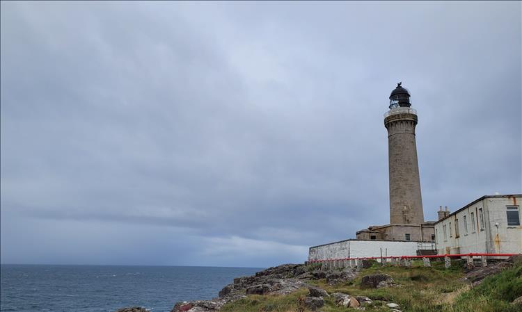 The lighthouse towers above the rocks and the choppy ocean