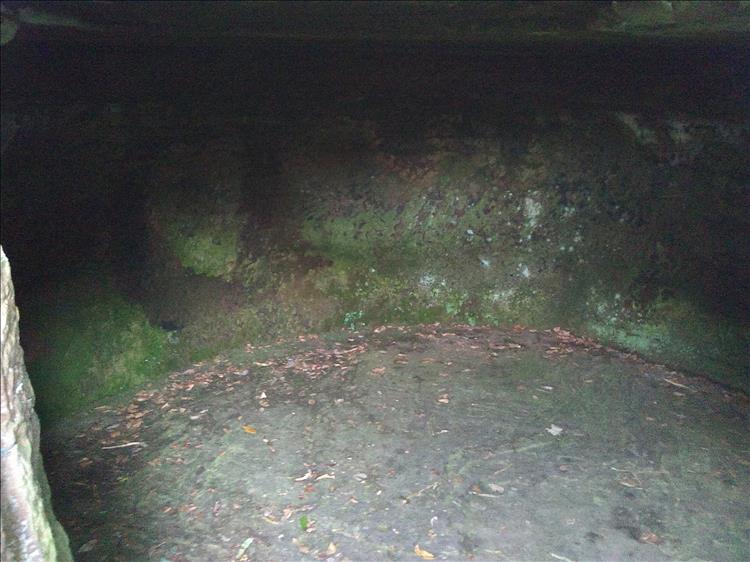 A dark man made hole in the rock is damp and musty