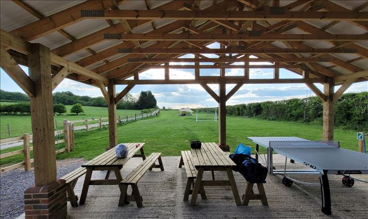 A covered area with table benches and a ping-pong table