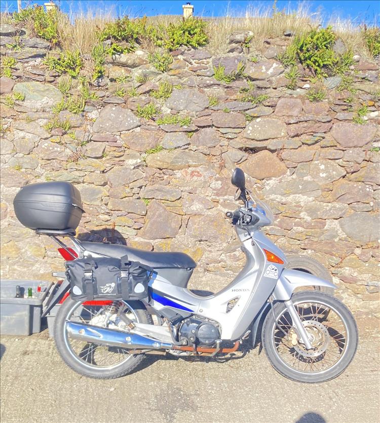 A Honda Innova in silver with just a top box and small saddle bags ready to tour