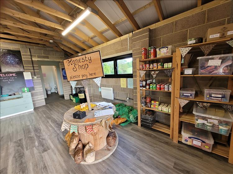 A set of wooden shelves filled with food basics like beans and crisps inside the basic building