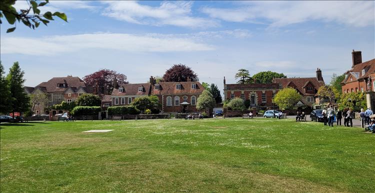 Smart older brick houses around a green look lovely with salisbury's cathedral walls