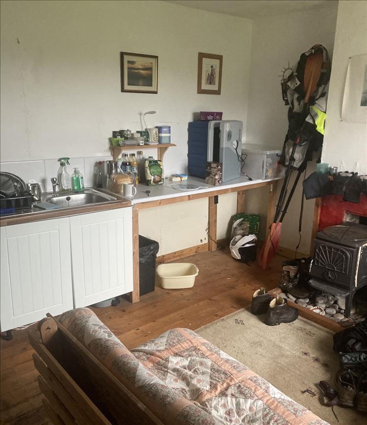 Inside the bothy is a humble sink, woodburner, chair and a few simple items