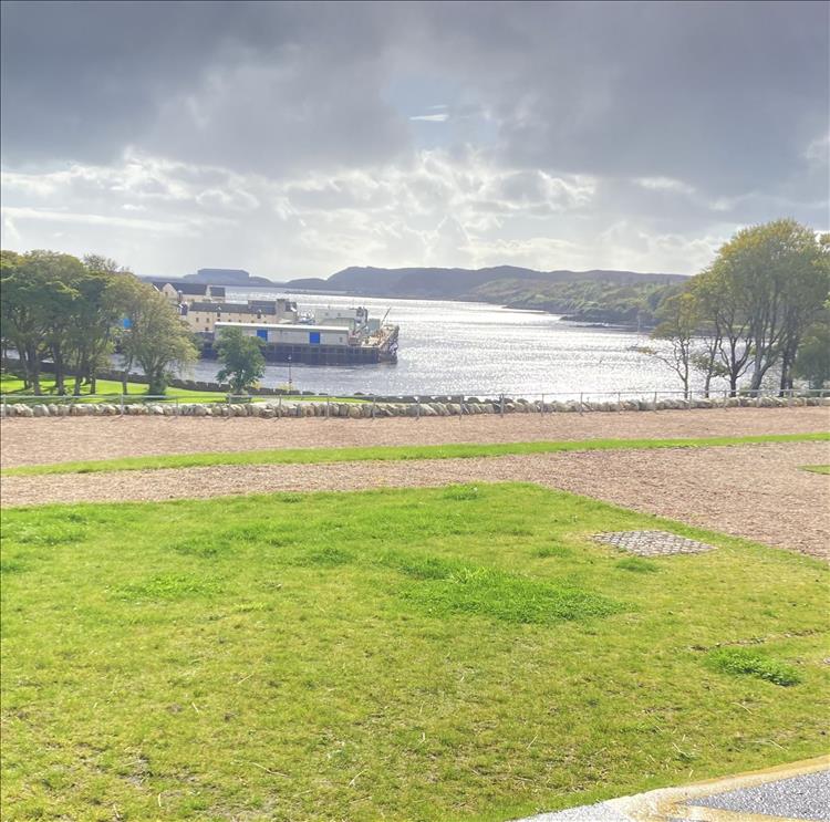 Looking out from the castle across smart grass and gravel parking we see the loch and Highland scenery