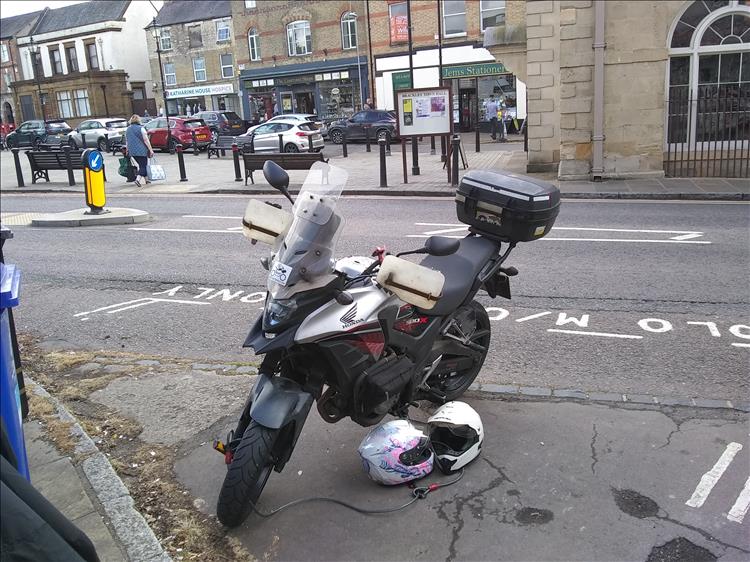 The CB500X parking in the motorcycle bay at Brackley with a few small shops behind