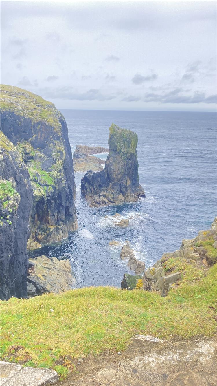 Steep cliffs, a towing outcrop and broiling seas create a dramatic scene