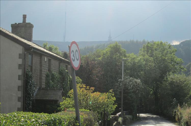 A stone house, narrow verdant lane and mist hills in the distance
