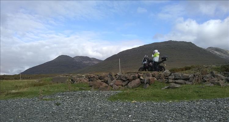 Looking up to Sharon taking pictures stood next to the CB500X on Mull