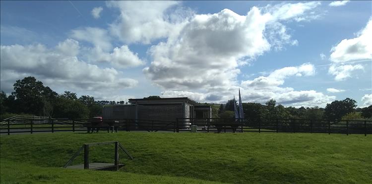 A timber clad oddly shaped building among rolling countryside