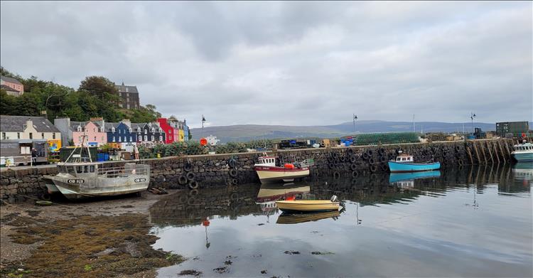We see the brightly painted houses but also the harbour wall covered in tyres and old fishing boats