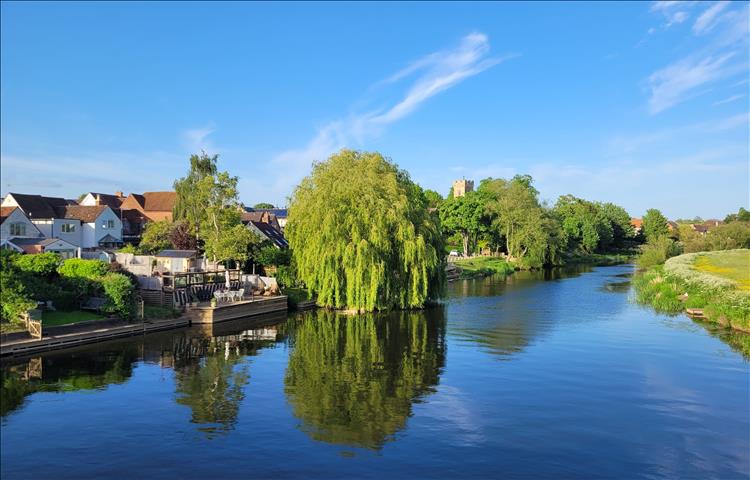 Seen from the bridge beautiful trees and houses are reflected in the water