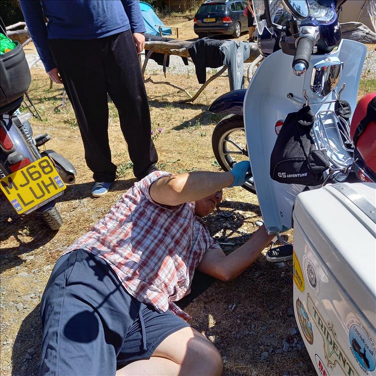 Bogger crawls under a C125 Cub as he adjusts the tappets