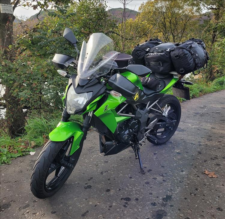 The Z250SL with luggage on the back in the countryside with trees and hills