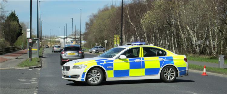 A police car parked across a main road blocking the traffic for reasons unknown